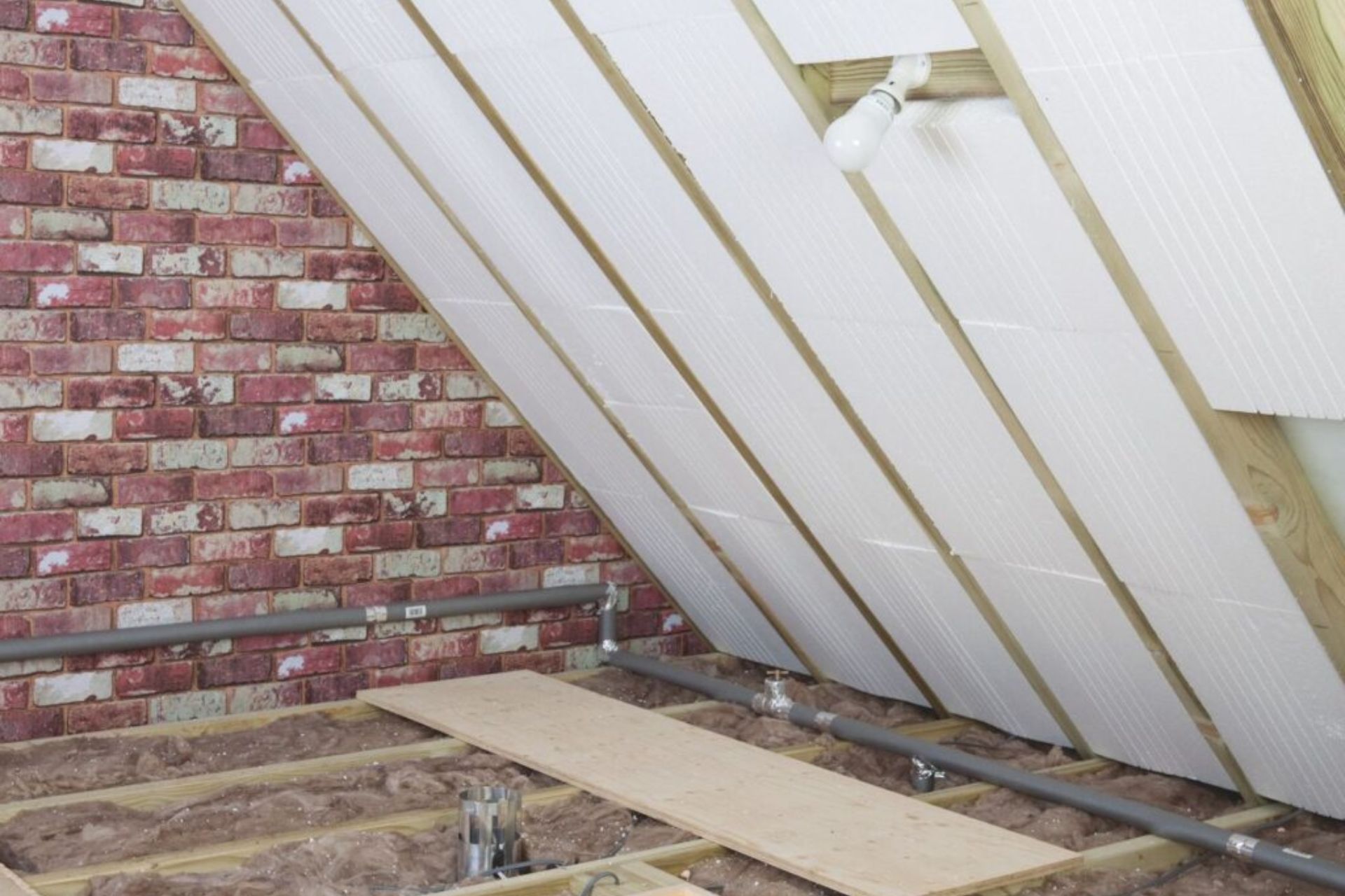 A room featuring a textured brick wall with visible insulation materials, creating an industrial and unfinished aesthetic.