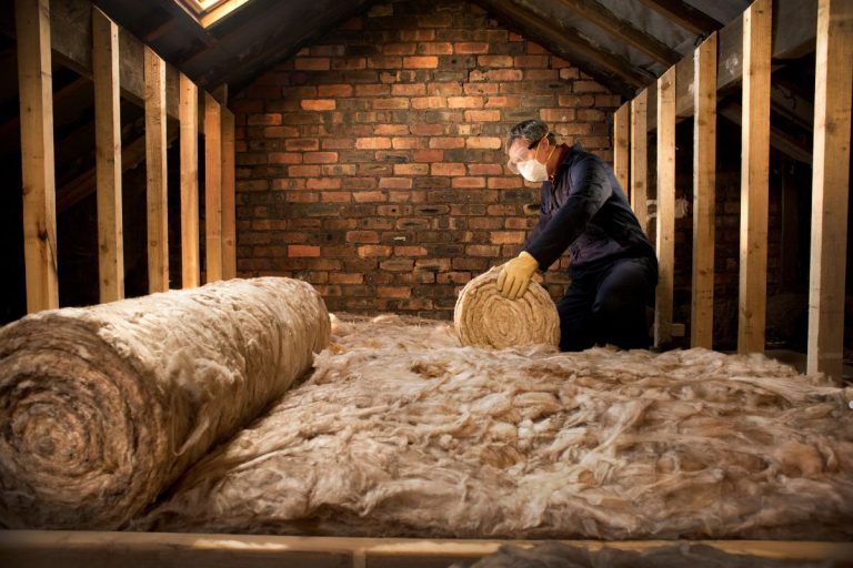 A man installs insulation in an attic as part of an insulation service.